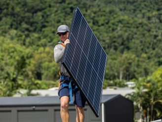 Man carrying a solar panel — Solar Power Systems in Proserpine, QLD