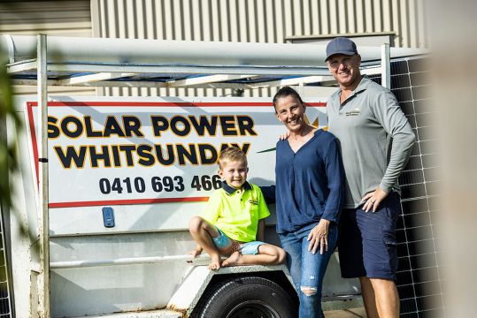 A family standing in front of Solar Power Whitsunday sign — Solar Power Systems in Proserpine, QLD